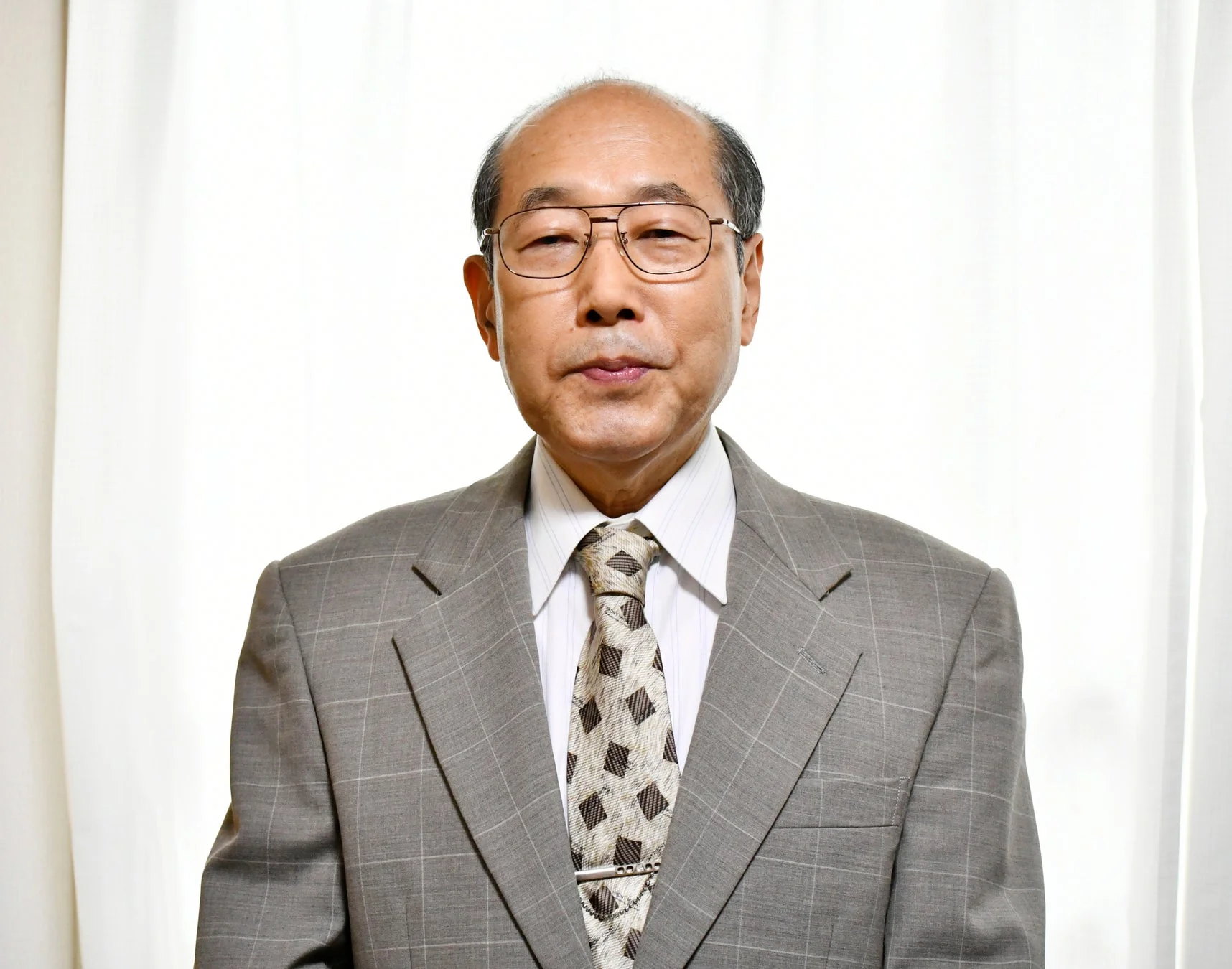 グレーのスーツを着用した桐谷広人氏のポートレート