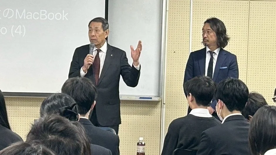 スーツの男性がマイクを持って話す